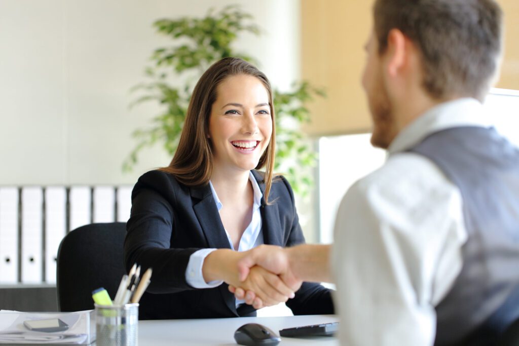Happy businesspeople handshaking after deal or interview at office